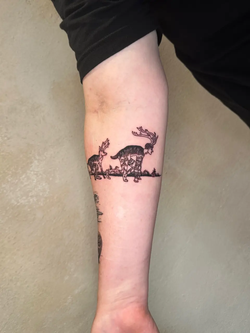 Band of antlered fantasy creatures with patterned legs and small plants around the forearm.