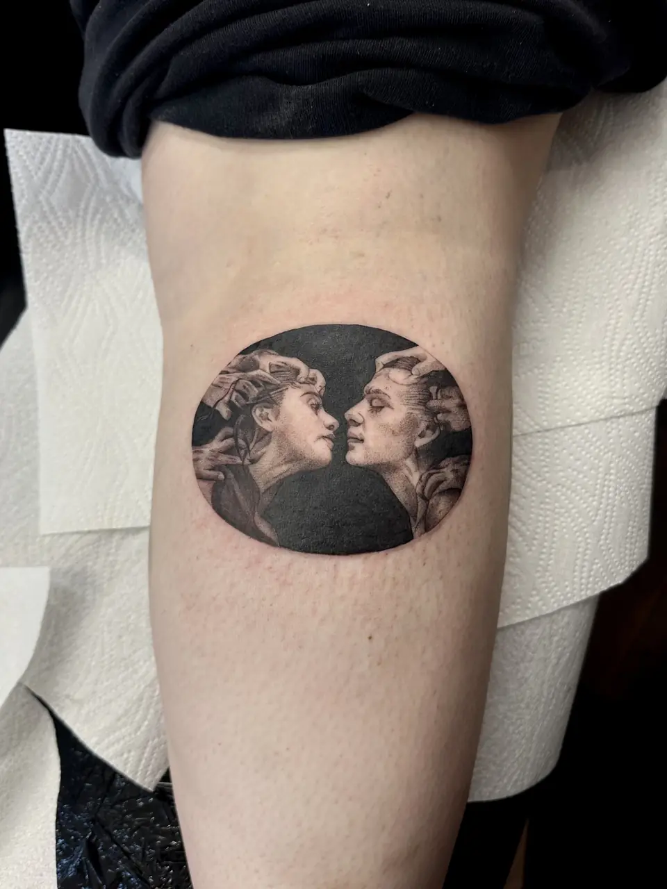 Two facing classical sculptural portraits inside a dark oval on the leg.