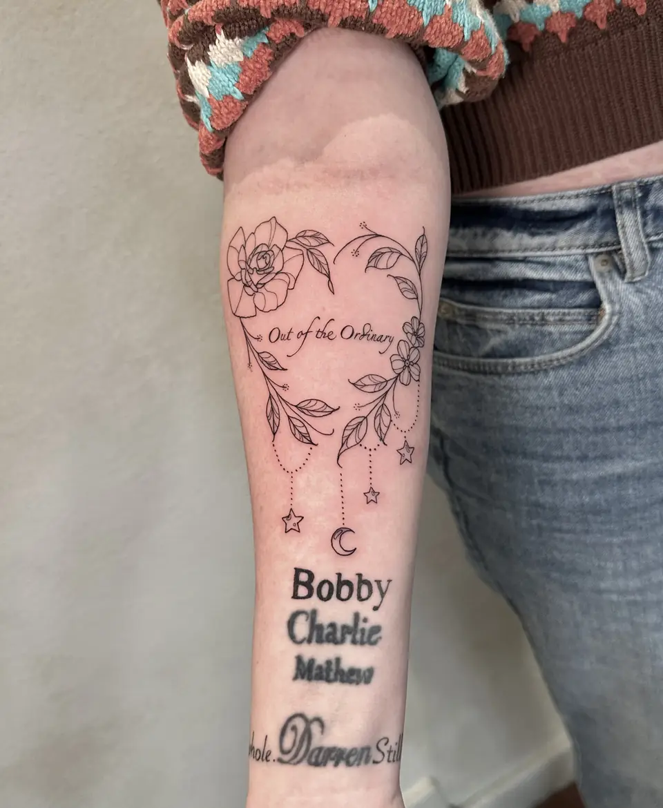 Floral heart surrounding script, with hanging stars and a crescent moon on the forearm.