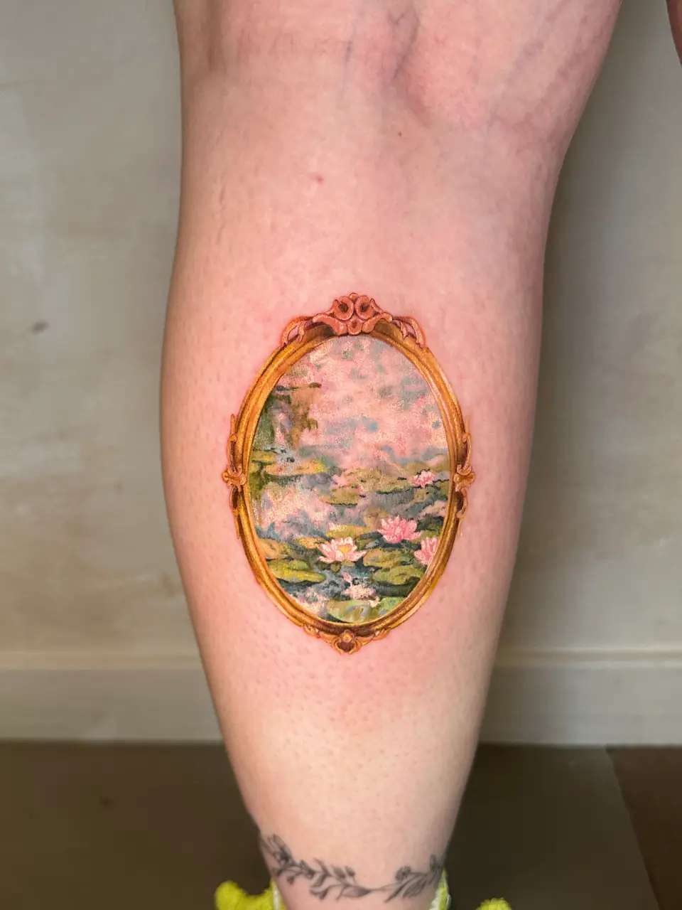 Colour water-lily pond painting inside an ornate gold oval frame on the calf.