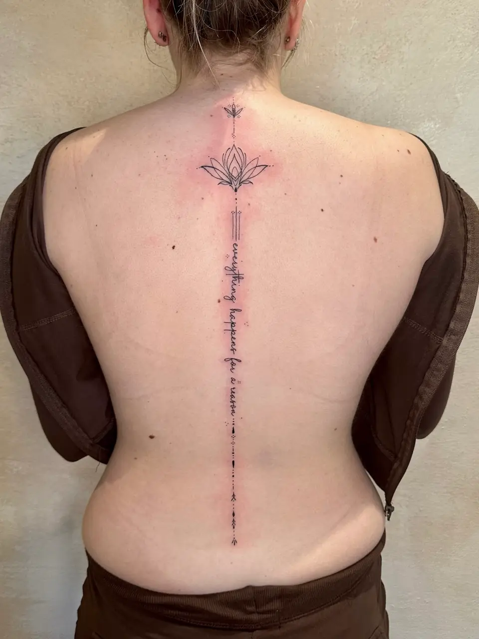 Fine-line lotus above vertical script and delicate ornamental marks down the spine.