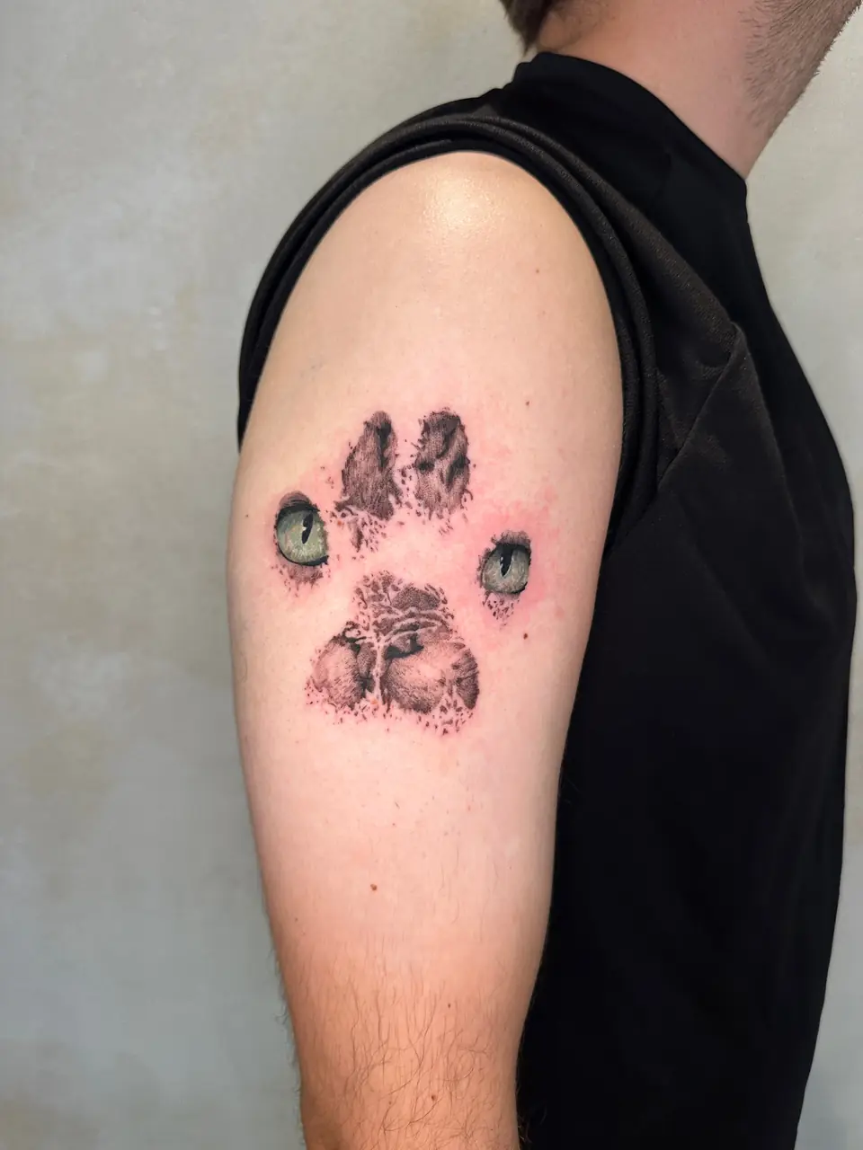 Textured paw print incorporating two green animal eyes on the upper arm.