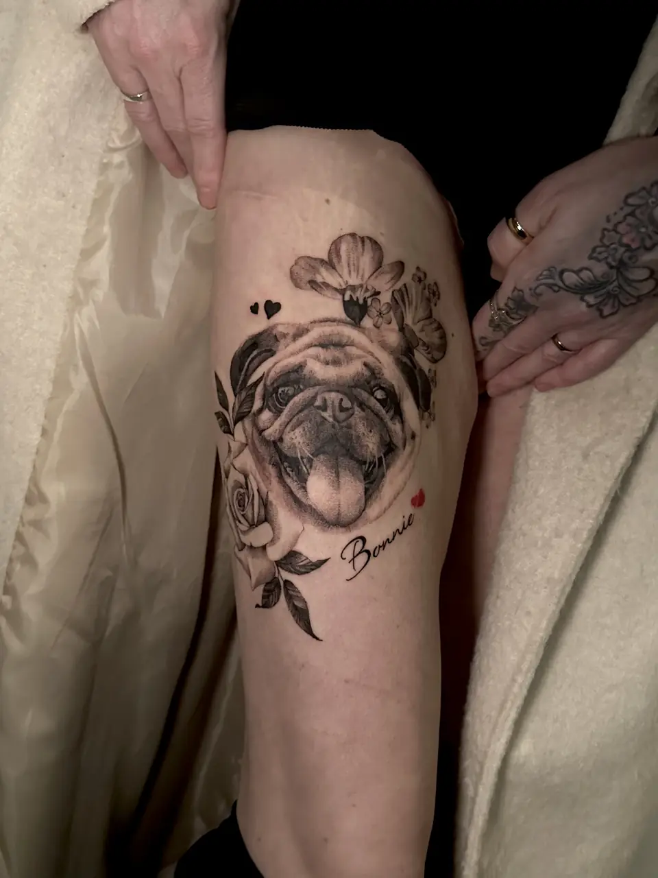 Realistic pug portrait with flowers, hearts and the name Bonnie on the thigh.