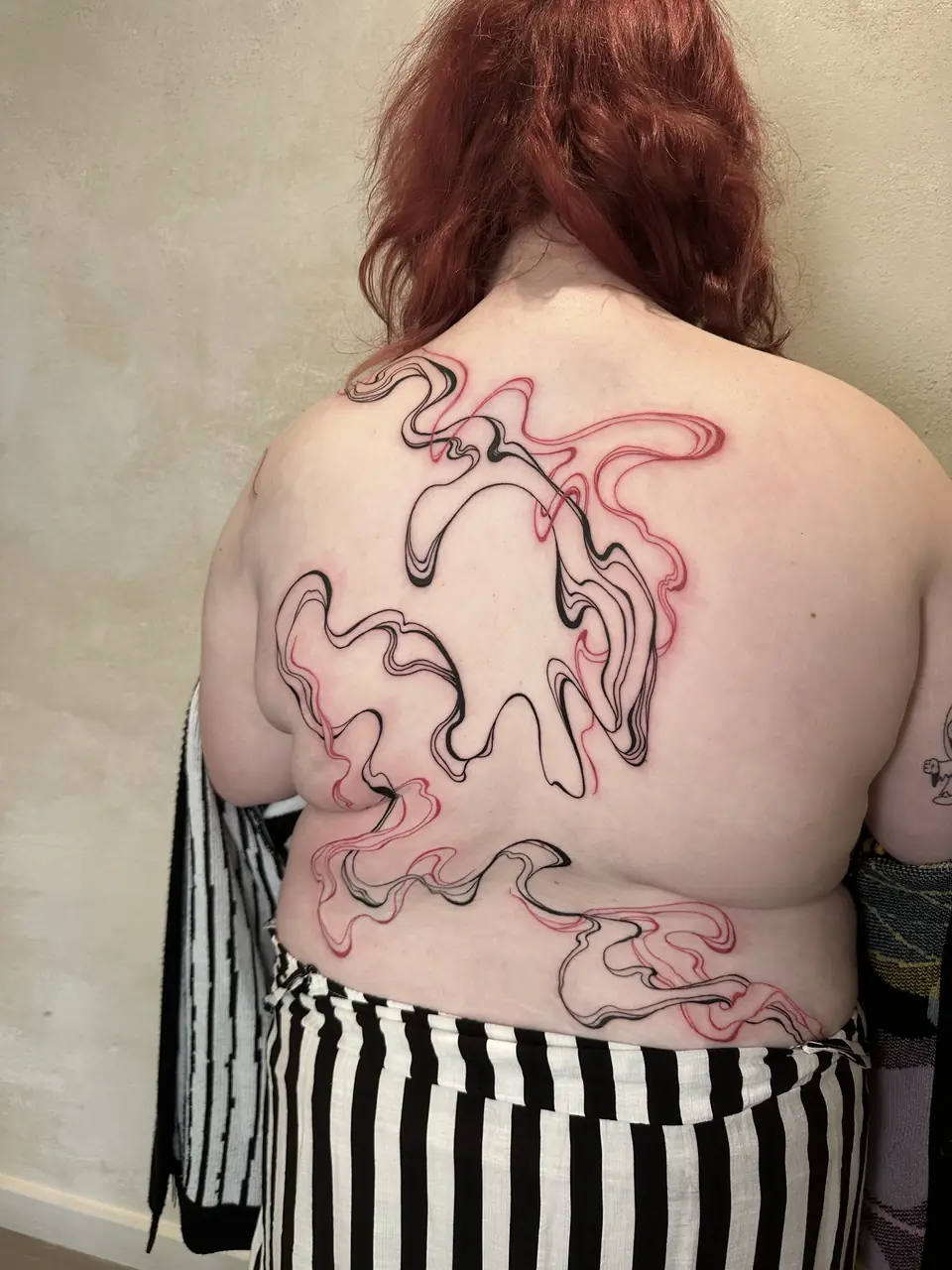 Flowing red and black abstract linework across the back.
