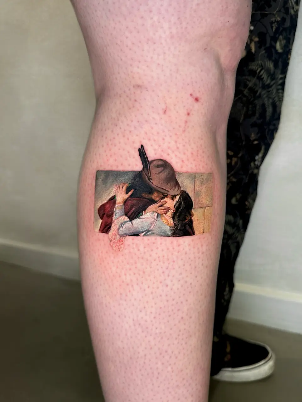 Small colour painting of an embracing couple kissing, set in a rectangular panel on the calf.