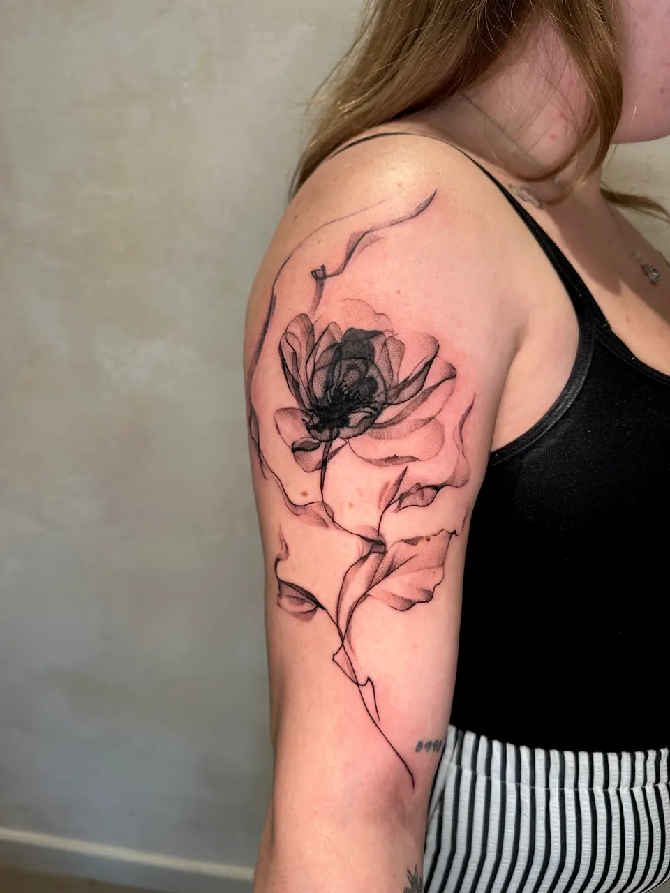 Large shaded flower with translucent-looking petals and flowing fine-line leaves on the upper arm.
