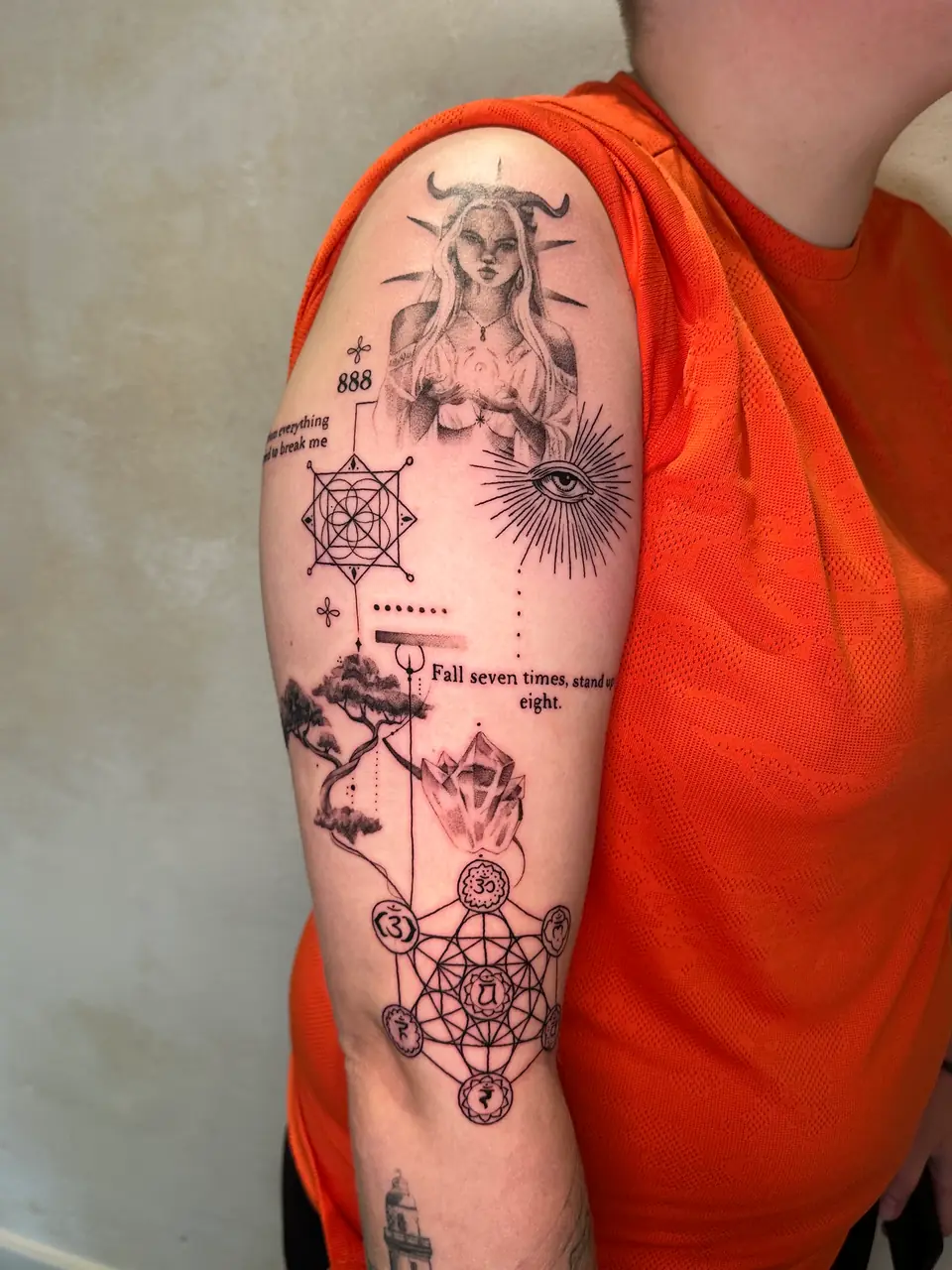 Symbolic upper-arm composition with a horned figure, radiant eye, geometric patterns, tree and crystals.