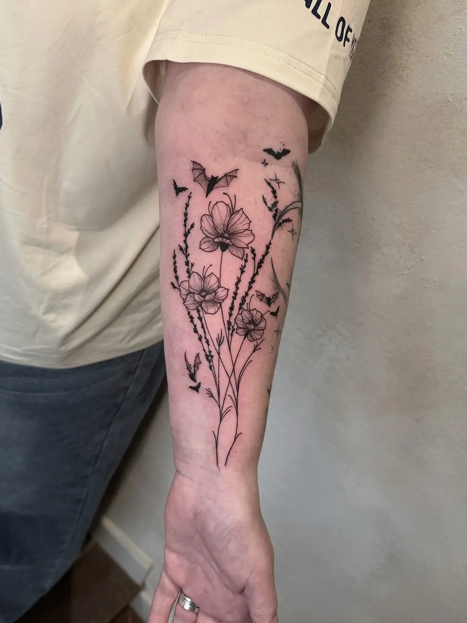 Fine-line wildflowers and tall stems with small flying bats along the forearm.