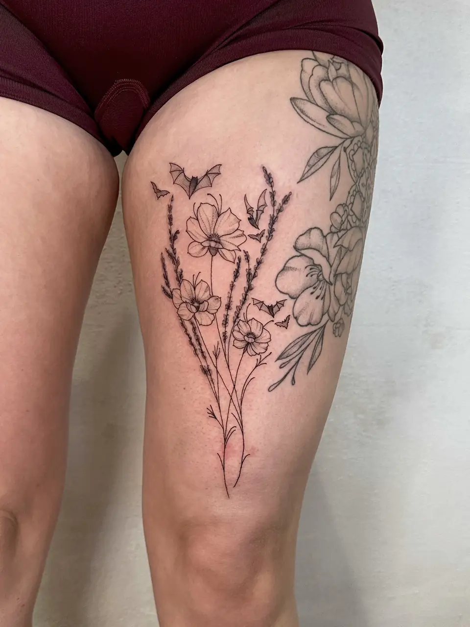 Fine-line wildflowers and tall stems with small flying bats on the thigh.