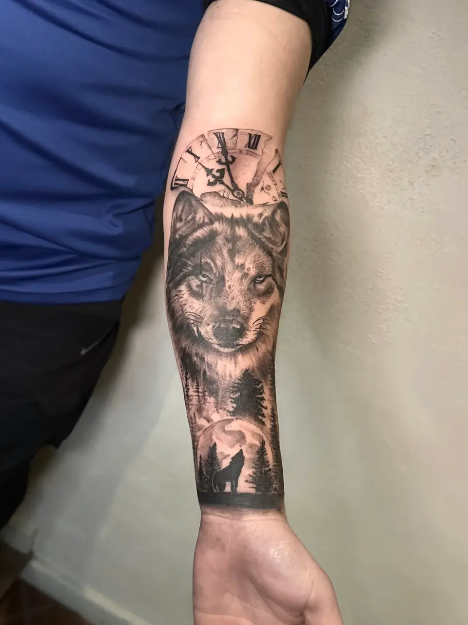 Wolf portrait above a forest, howling wolf and moon, with a broken Roman numeral clock on the forearm.