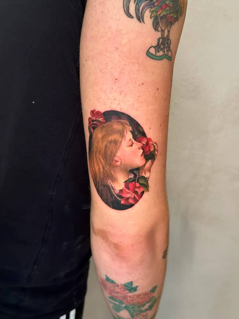 Colour profile of a woman smelling red roses against a dark oval background on the arm.